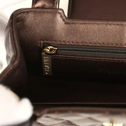 Small bag interior pocket with gold zipper pull and textured brown leather trim