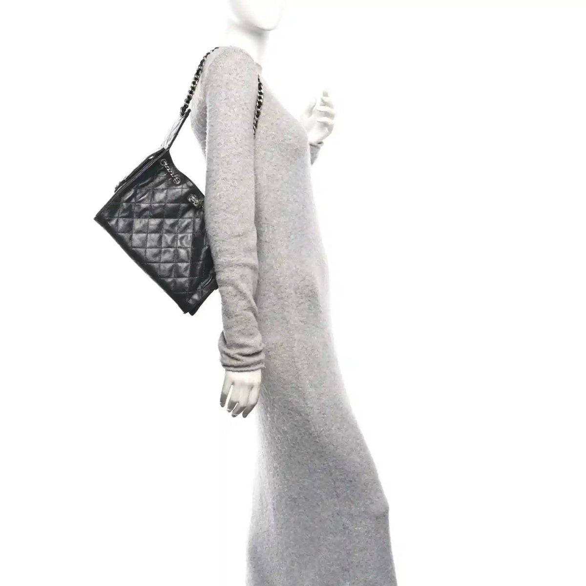 Chanel quilted black leather handbag with chain strap, held at side