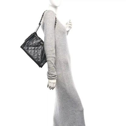 Chanel quilted black leather handbag with chain strap, held at side
