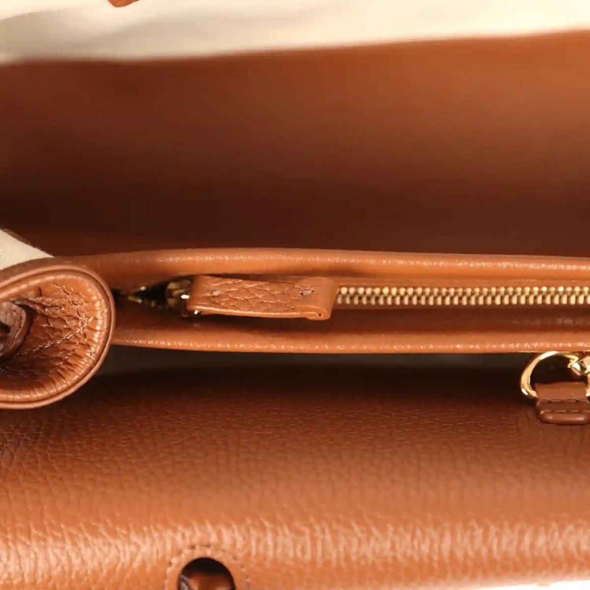 Chanel small tote bag interior close-up with gold zipper pull and leather snap tab