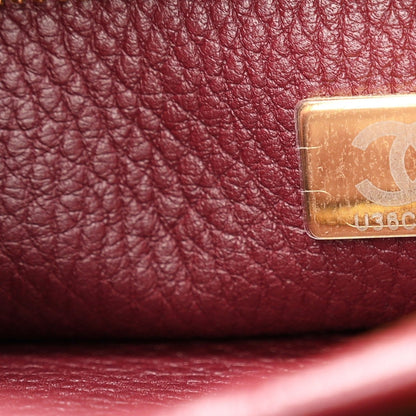 Chanel burgundy leather with gold-tone logo plate near stitched seam