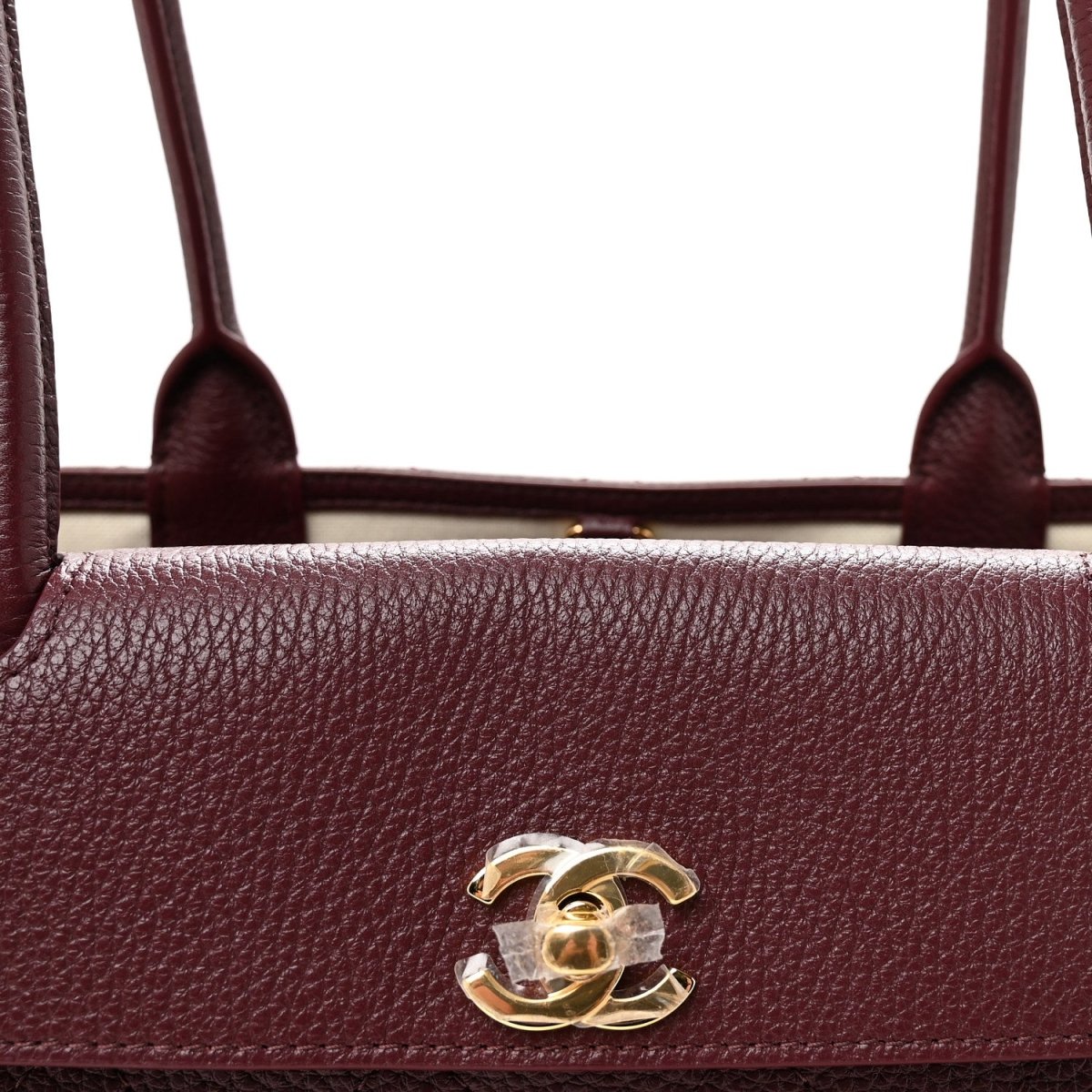 Burgundy grained leather bag front with gold CC logo and top handle openings