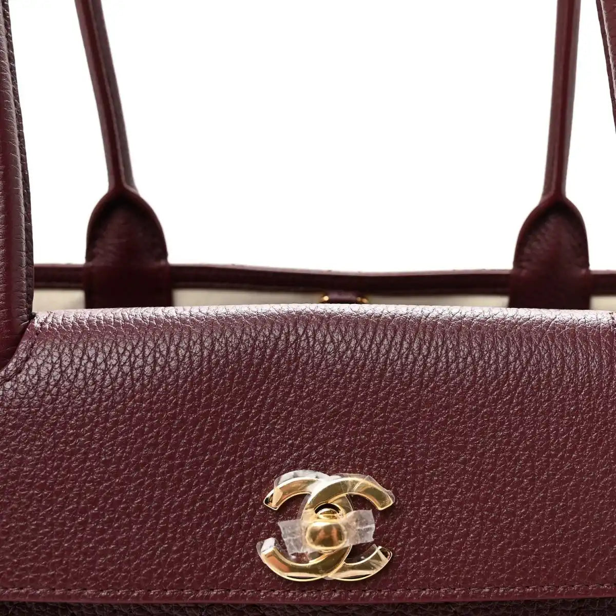 Burgundy grained leather bag front with gold CC logo and top handle openings