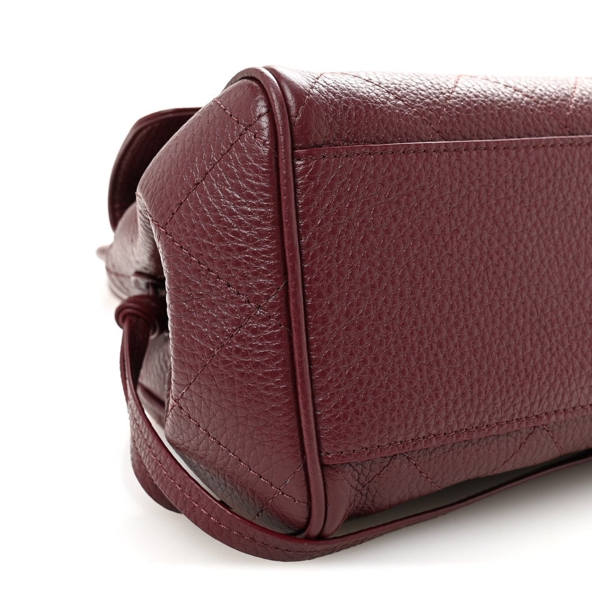 Burgundy grained leather bag corner with stitched seam and flap edge