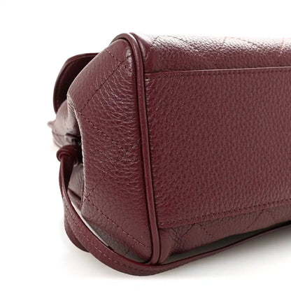 Burgundy grained leather bag corner with stitched seam and flap edge