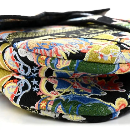 Embroidered top flap with black background and multicolor zodiac motifs; quilted edge