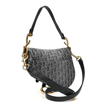 Black jacquard saddle bag with flap, long strap, and gold-tone hardware