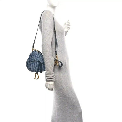 Dark blue jacquard saddle bag with gold hardware and shoulder strap, side view