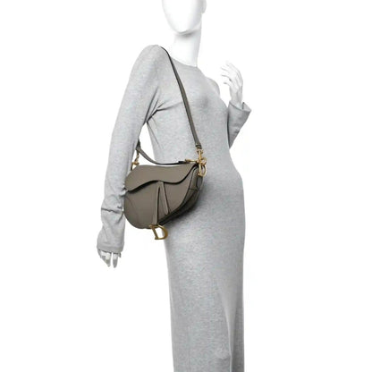Dark green grained calfskin saddle bag worn crossbody with gold-tone chain strap