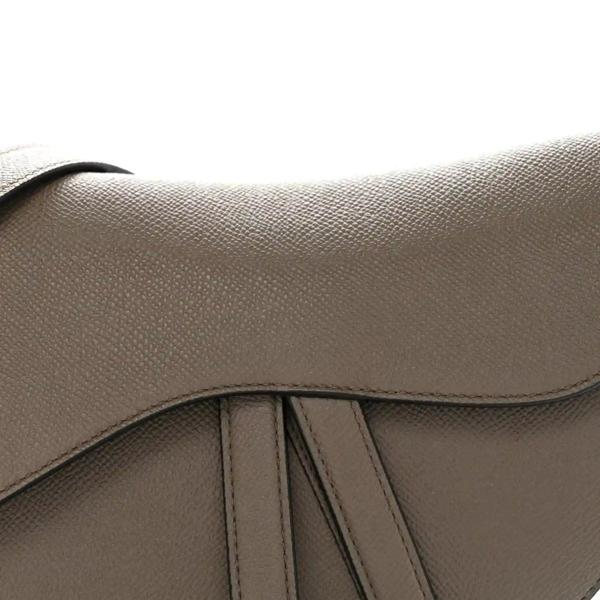 Close-up of flap seam and grained texture on dark green saddle bag