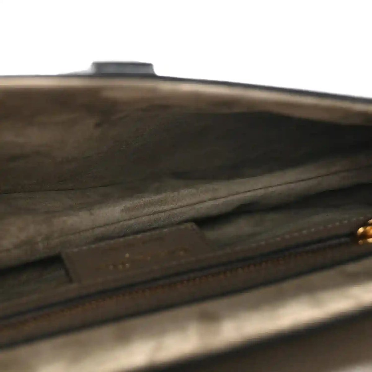 Close-up of grained leather edge and top stitching on dark green saddle bag
