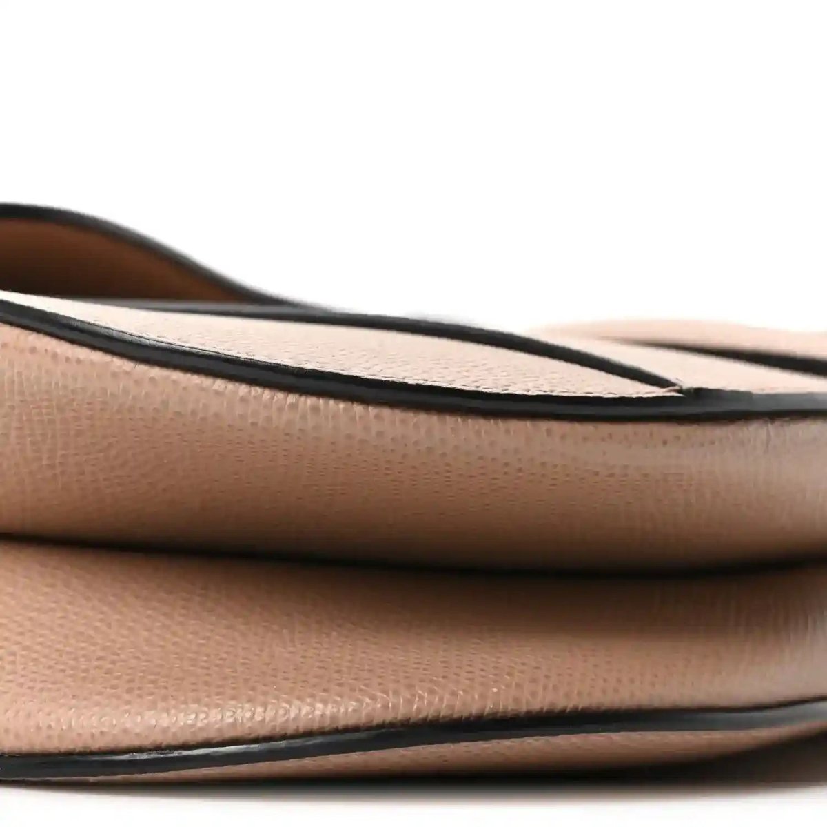 Bottom edge close-up of light pink grained leather saddle bag with black trim