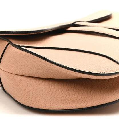Light pink grained calfskin saddle bag with black-trim shoulder strap and flap