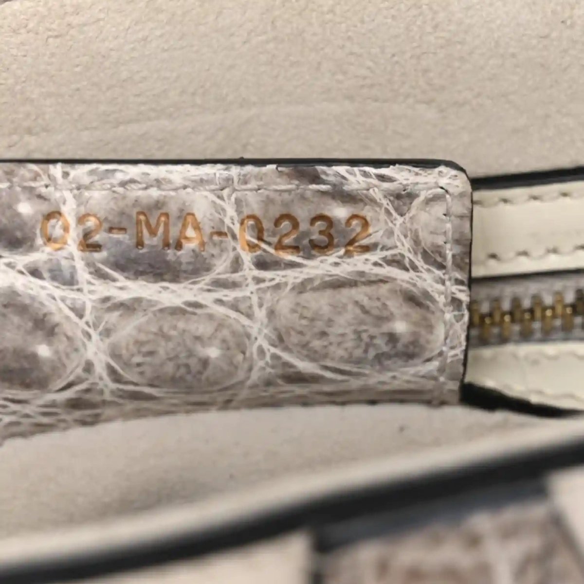 Crocodile-effect leather saddle bag close-up of stamped panel and stitched edge
