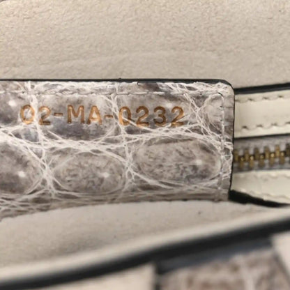 Crocodile-effect leather saddle bag close-up of stamped panel and stitched edge