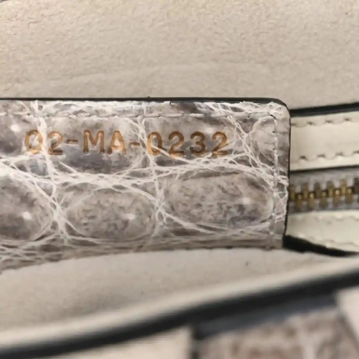 Crocodile-effect leather saddle bag close-up of stamped panel and stitched edge