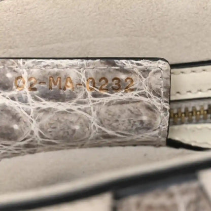 Crocodile-effect leather saddle bag close-up of stamped panel and stitched edge