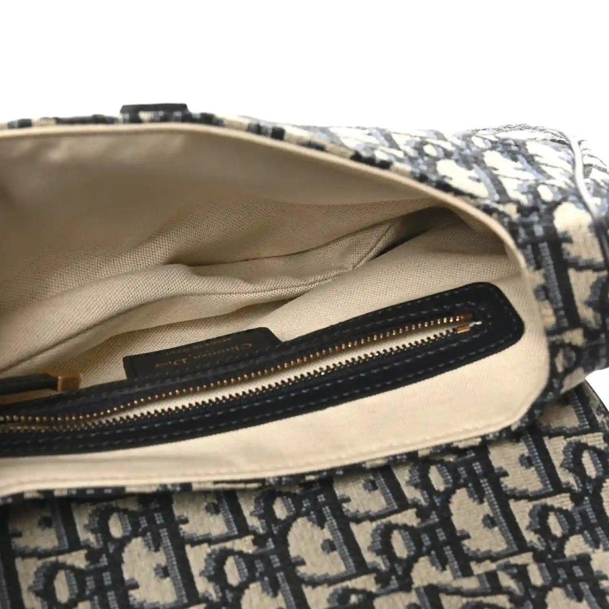 Saddle shoulder bag interior with beige lining and black zip pocket and gold zipper