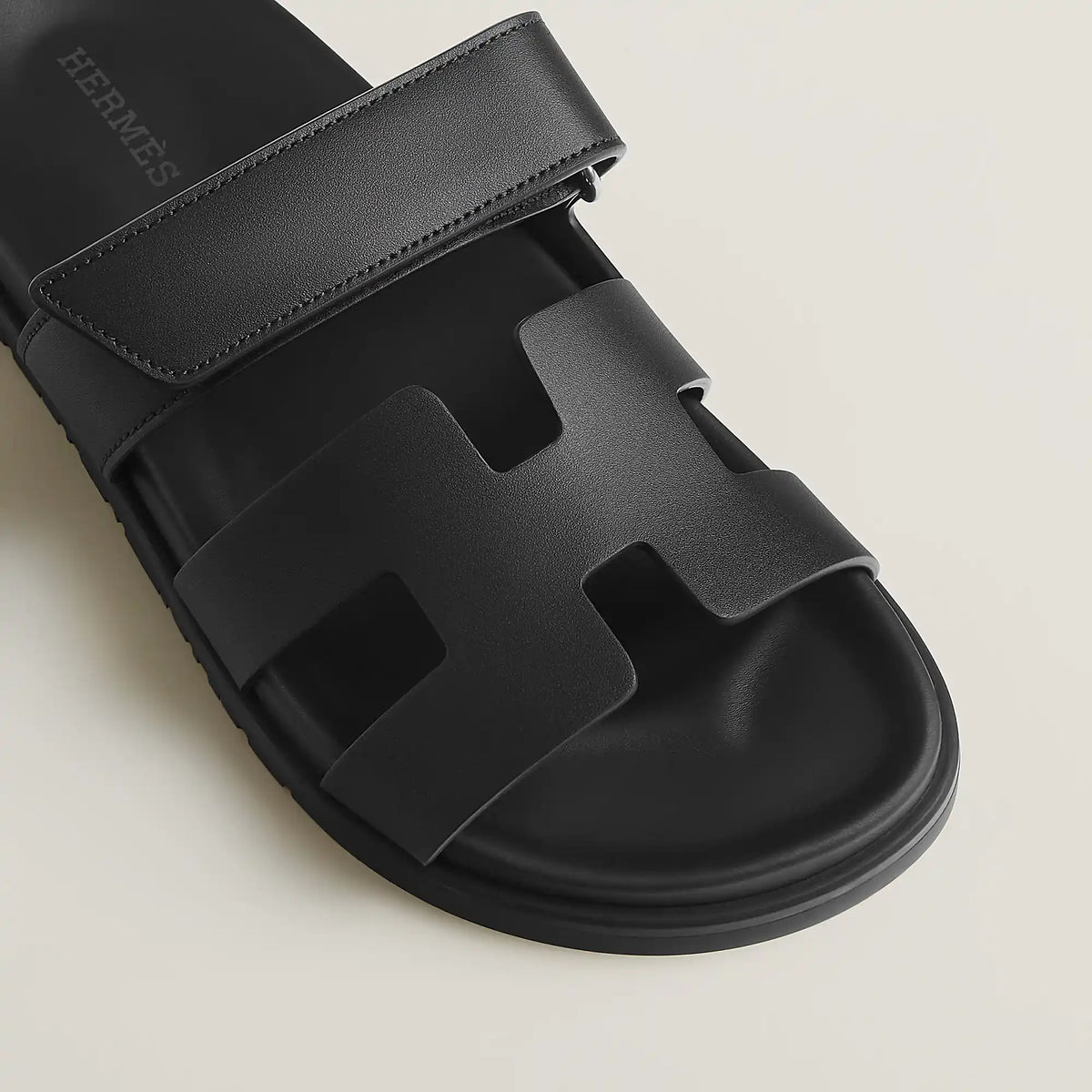 Black suede slide sandals close-up of wide strap and molded footbed