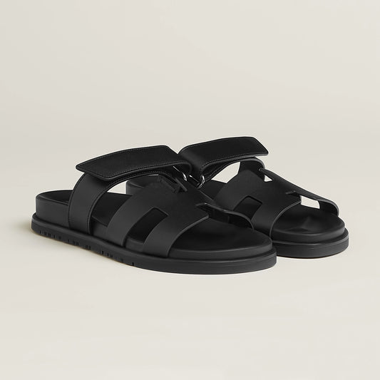 Black suede slide sandals with adjustable buckle strap and cushioned footbed