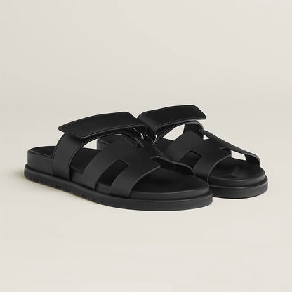 Black suede slide sandals with adjustable buckle strap and cushioned footbed