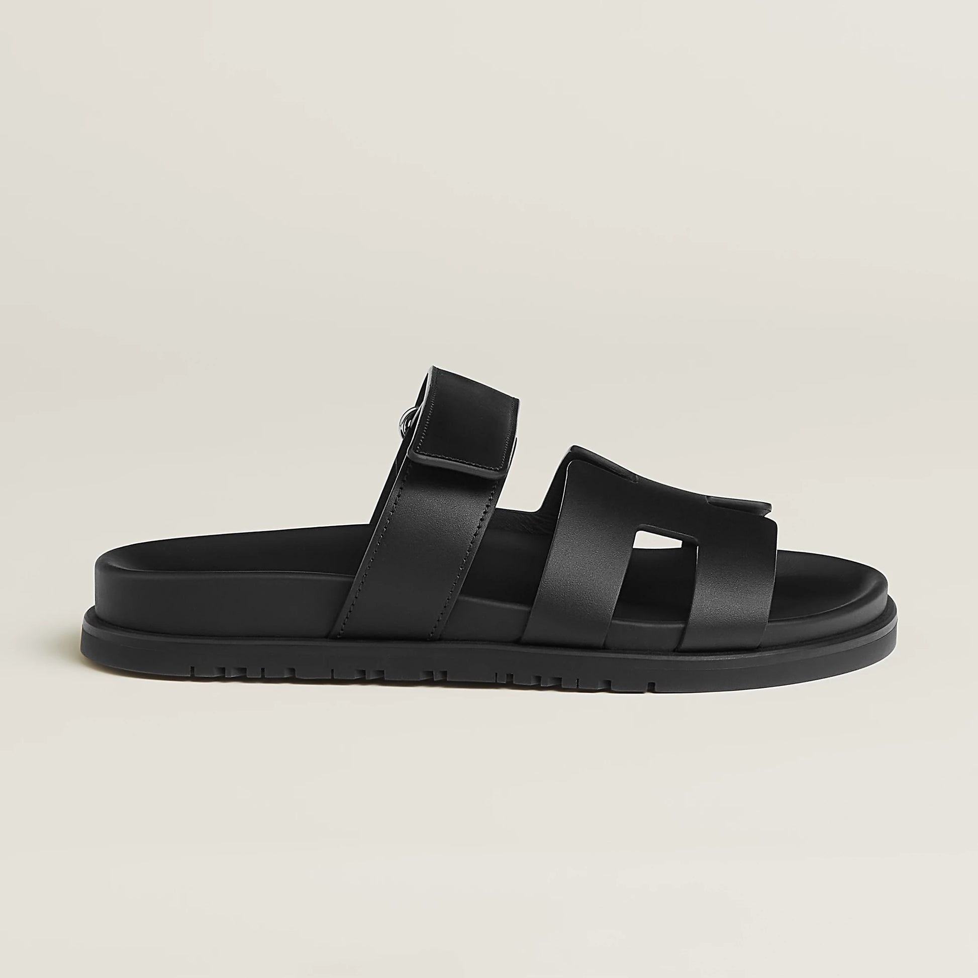 Black suede slide sandals with wide straps, buckle closure, and flat rubber sole