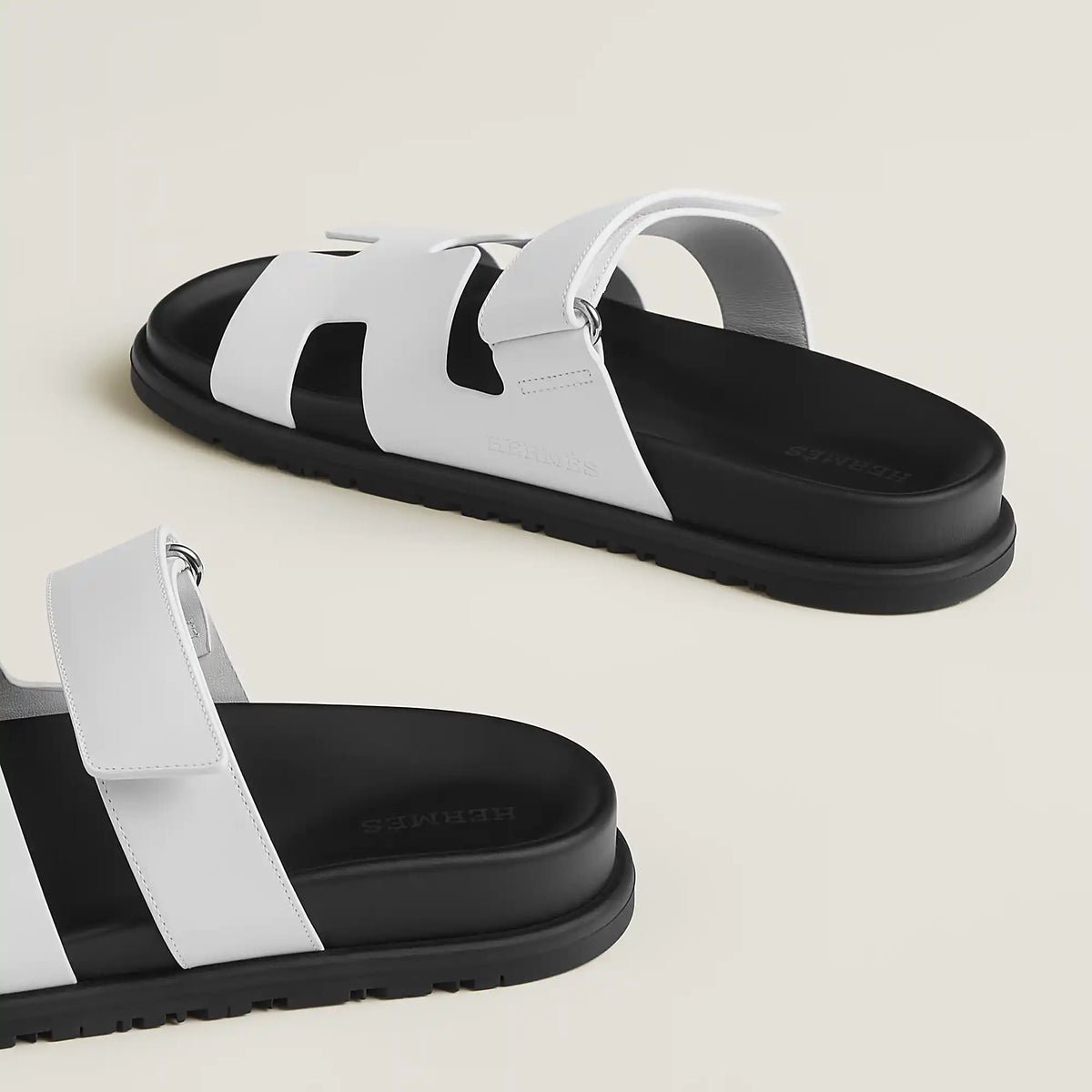 White suede slide sandals with wide straps and black-edged chunky sole, buckle closure
