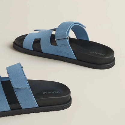 Blue suede slide sandal with wide cross straps and black rubber sole