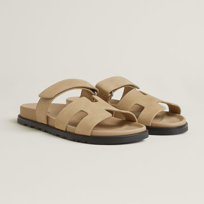 Beige suede slide sandal with wide crossover straps and black rubber sole