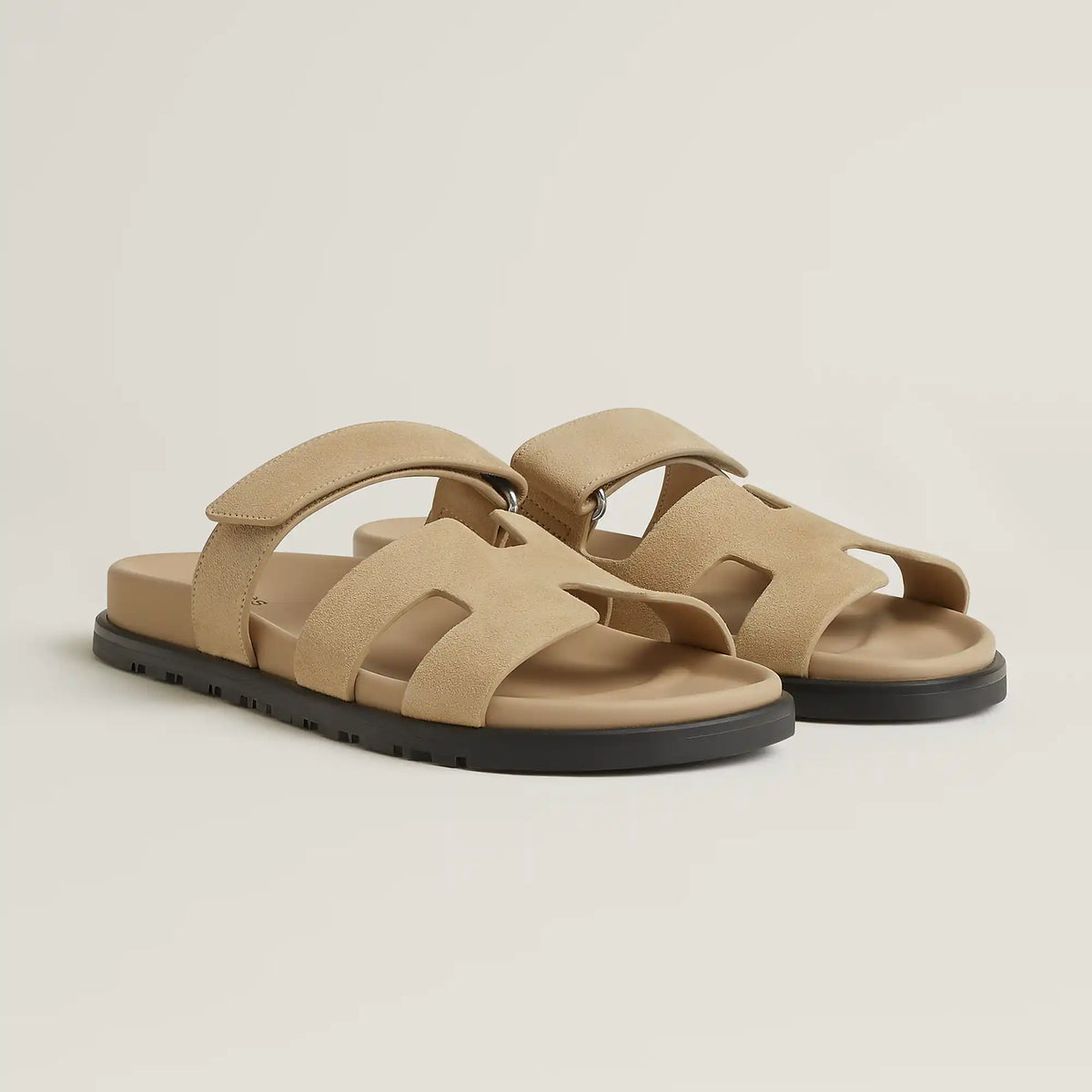 Beige suede slide sandal with wide crossover straps and black rubber sole
