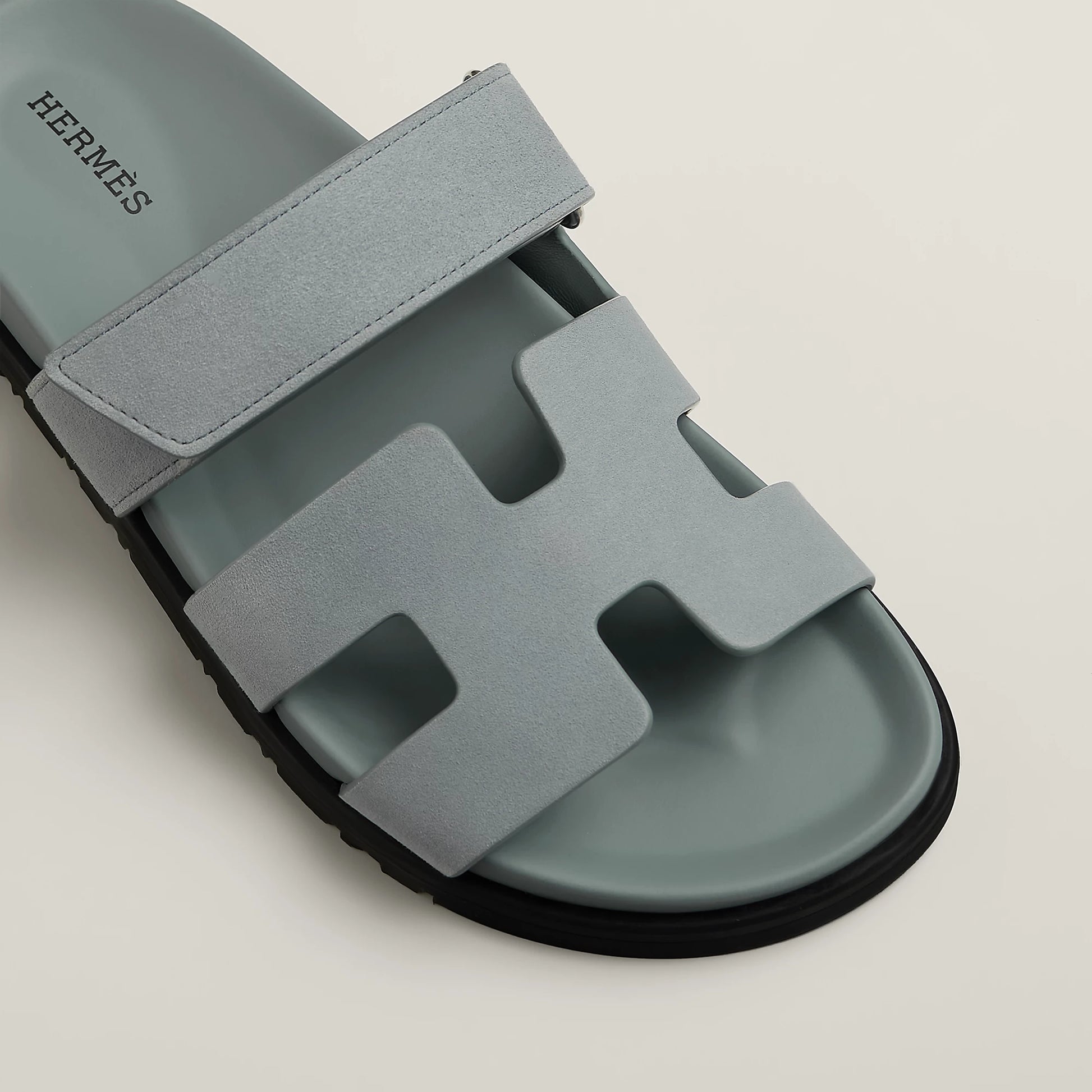 Light gray suede slide sandal with H-style cutout straps and black rubber sole