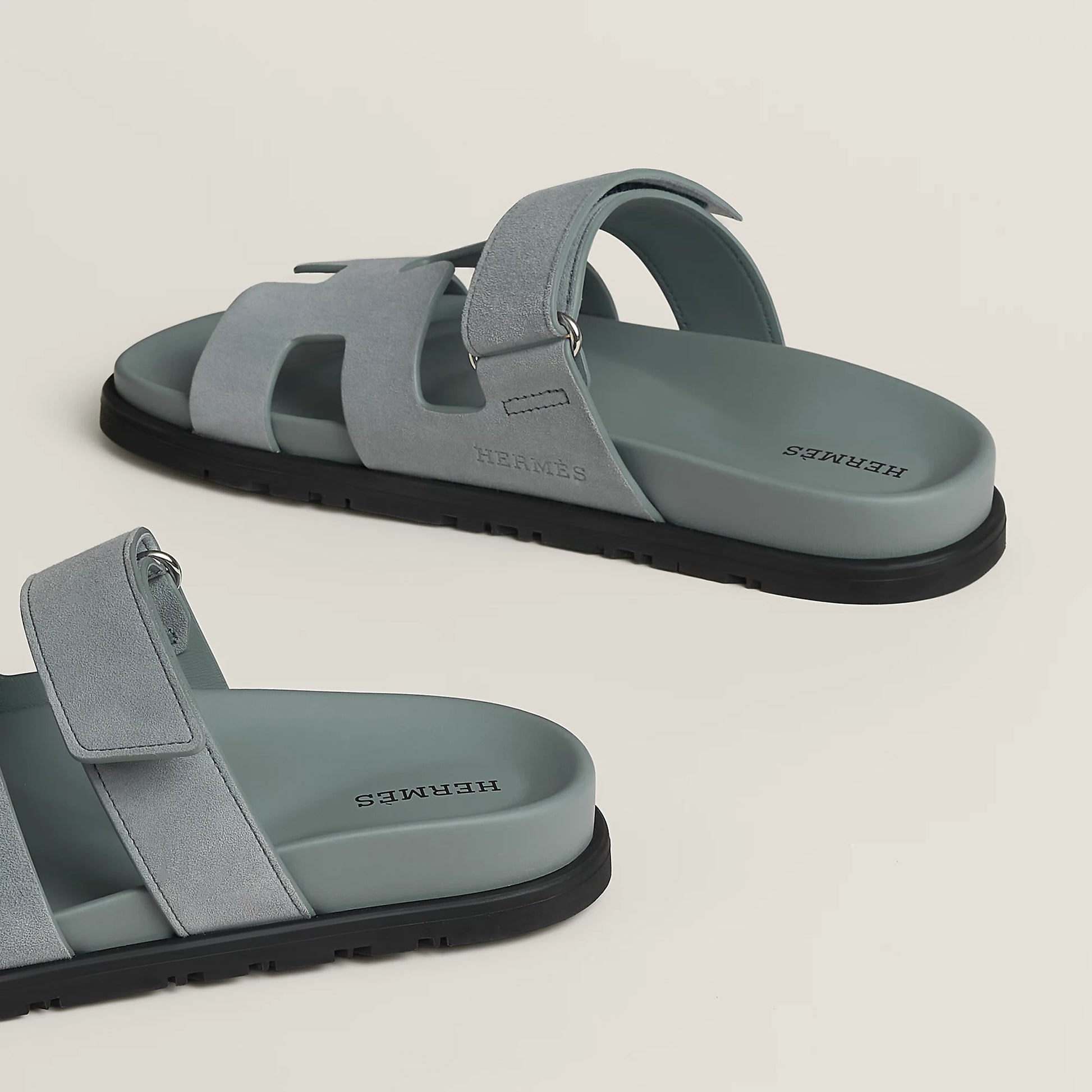 Light gray suede slide sandal with wide cross straps and black rubber sole