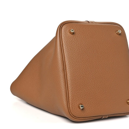 Calfskin leather tote with corner studs and gold lock hardware, angled view