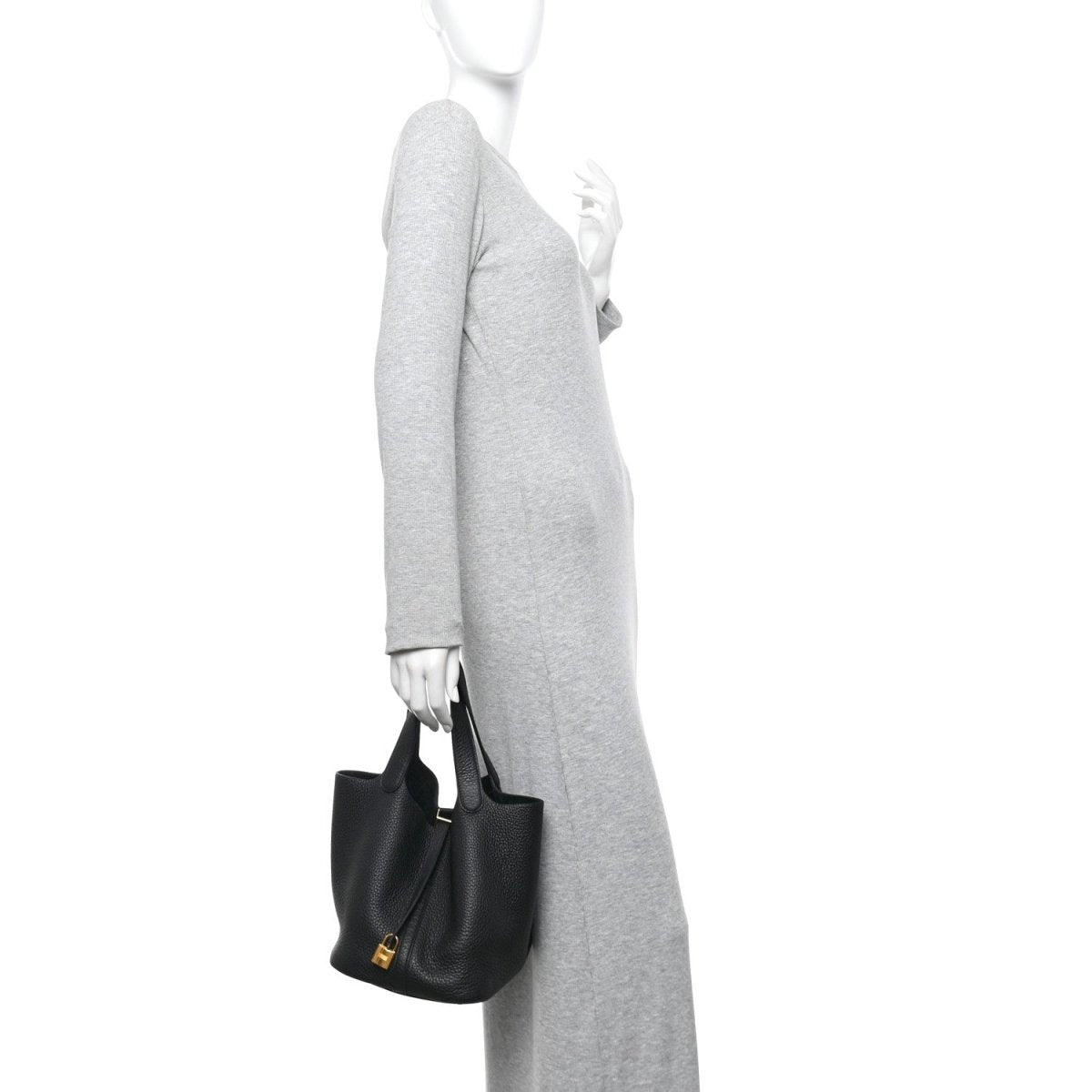 Black lock tote handbag with top handles, held at side by a person.