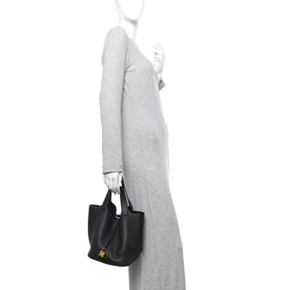 Black lock tote handbag with top handles, held at side by a person.