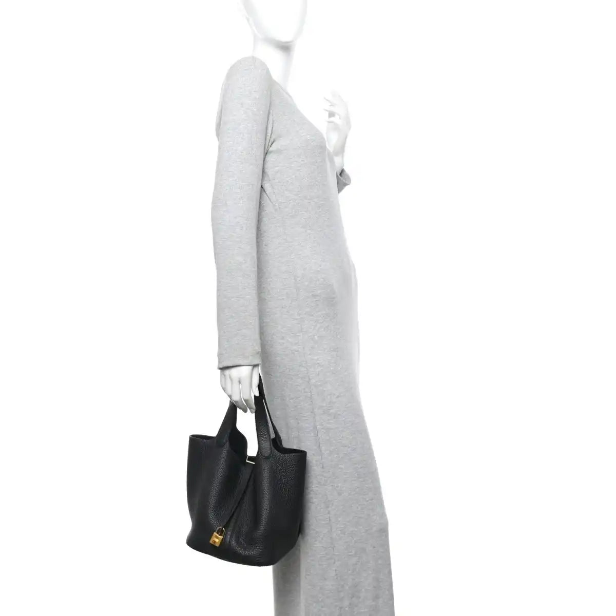 Black lock tote handbag with top handles, held at side by a person.