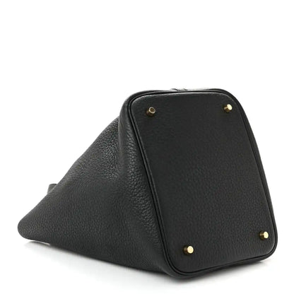Black pebbled leather tote handbag with gold-tone corner studs and angled shape.
