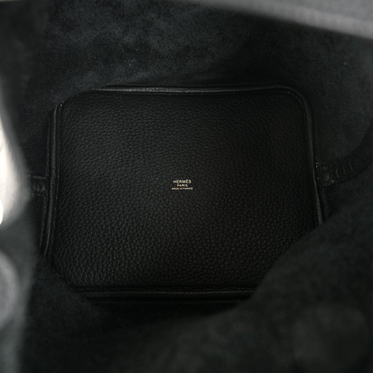 Black leather interior of a tote handbag with a small logo patch.