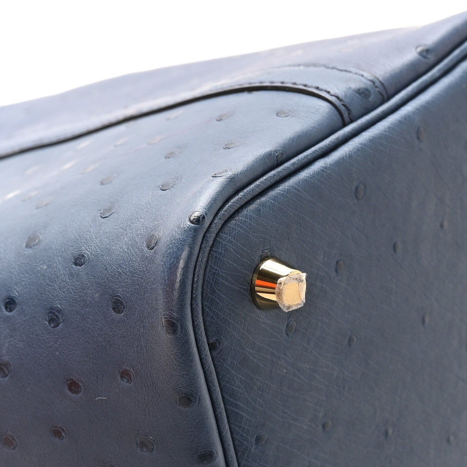 Blue ostrich leather bag corner with round gold-tone clasp hardware.