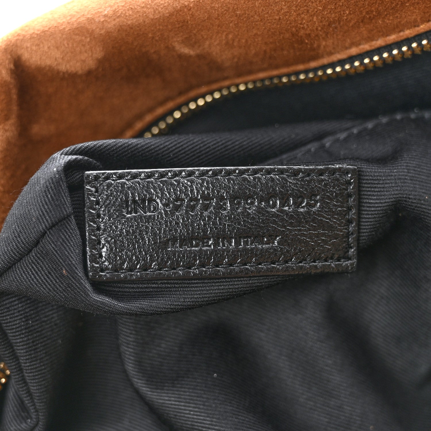 Saint Laurent suede shoulder bag interior label on dark fabric near zipper closure.