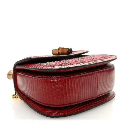 Red mini top-handle bag side view with flap, bamboo-look top accent, and textured trim.