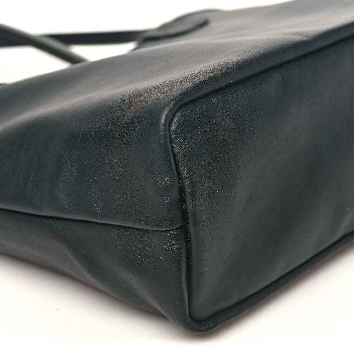 Black leather-like corner detail of a reversible mini tote bag with stitching.