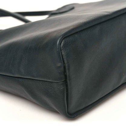 Black leather-like corner detail of a reversible mini tote bag with stitching.