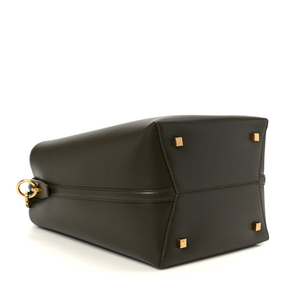 Shiny bucket bag with structured bottom and gold clasp hardware, dark leather.