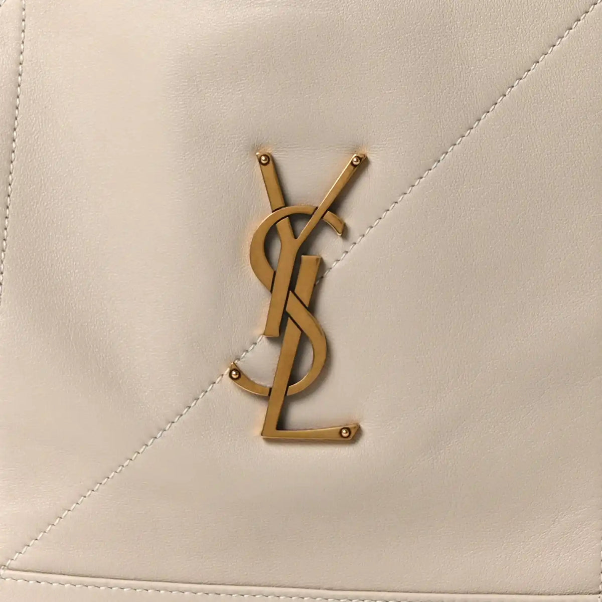 Gold YSL logo on cream lambskin tote bag panel with visible stitching