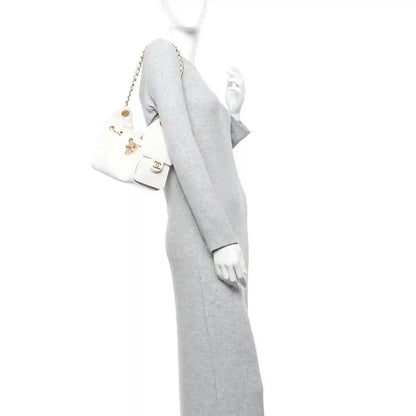 White quilted mini handbag worn on shoulder with gold-tone chain strap and small front pocket