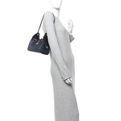 Handheld mini handbag with chain strap worn over grey outfit