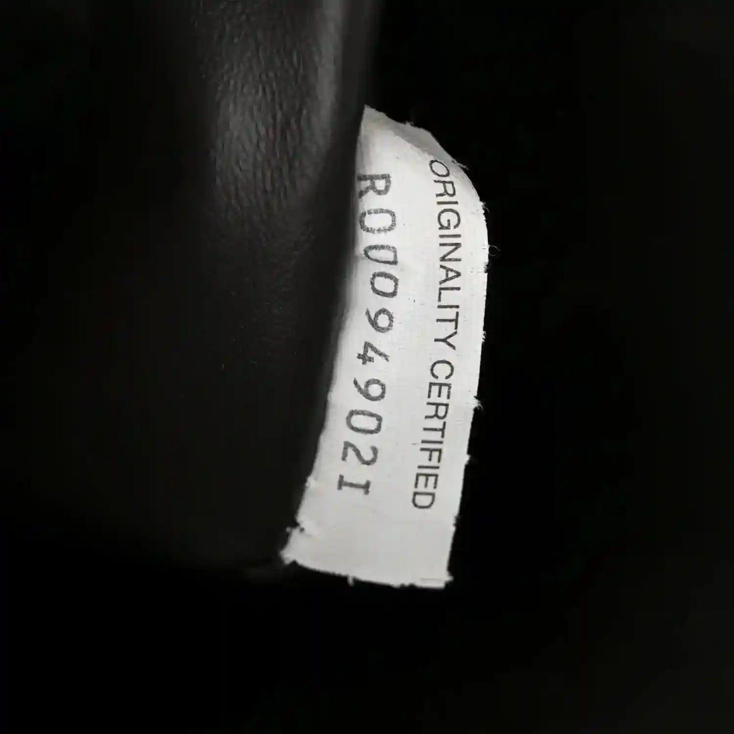 Originality card label on dark leather interior with stamped certification text
