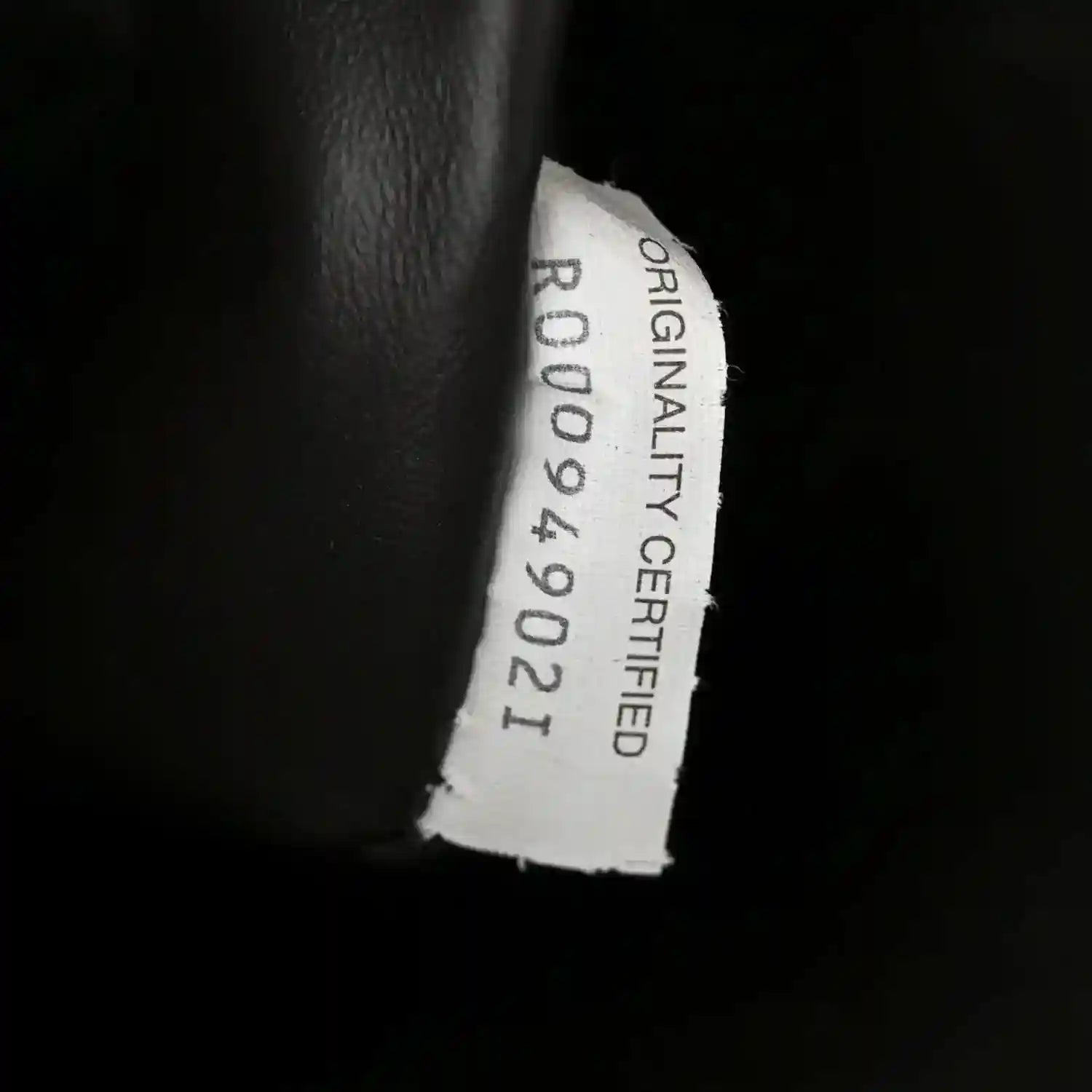 Originality card label on dark leather interior with stamped certification text
