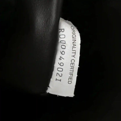 Originality card label on dark leather interior with stamped certification text